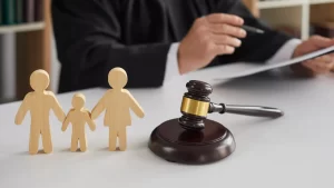 an adoption lawyer is holding a pen and paper with a gavel and a couple of wooden figures