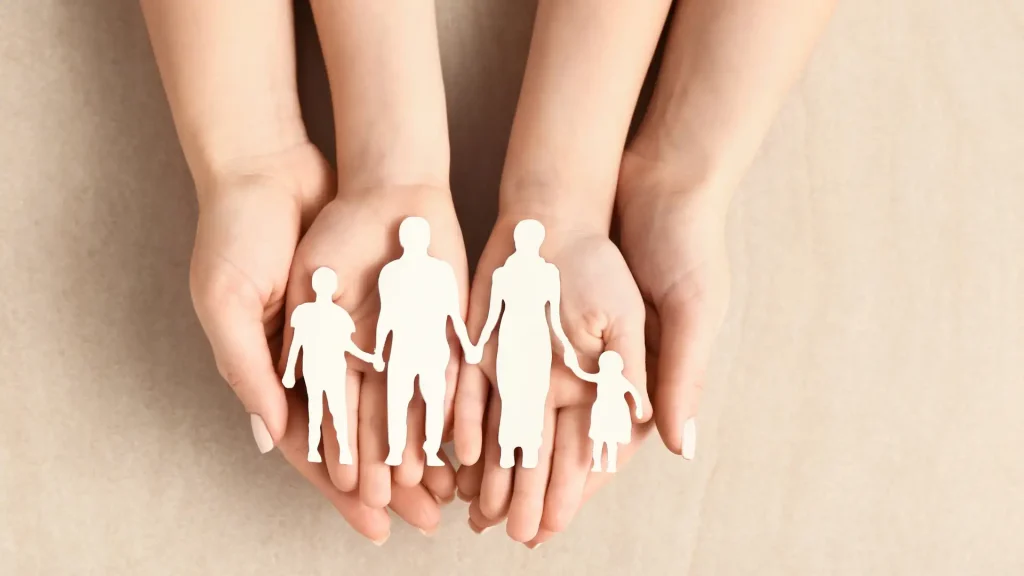 Hands holding paper cutout of a family representing protection and care.